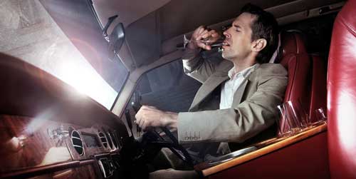 A man drinking alcohol while driving. 